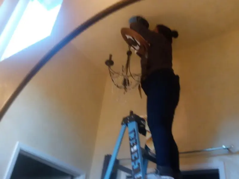 Electrician installing a chandelier in a Burlington residence